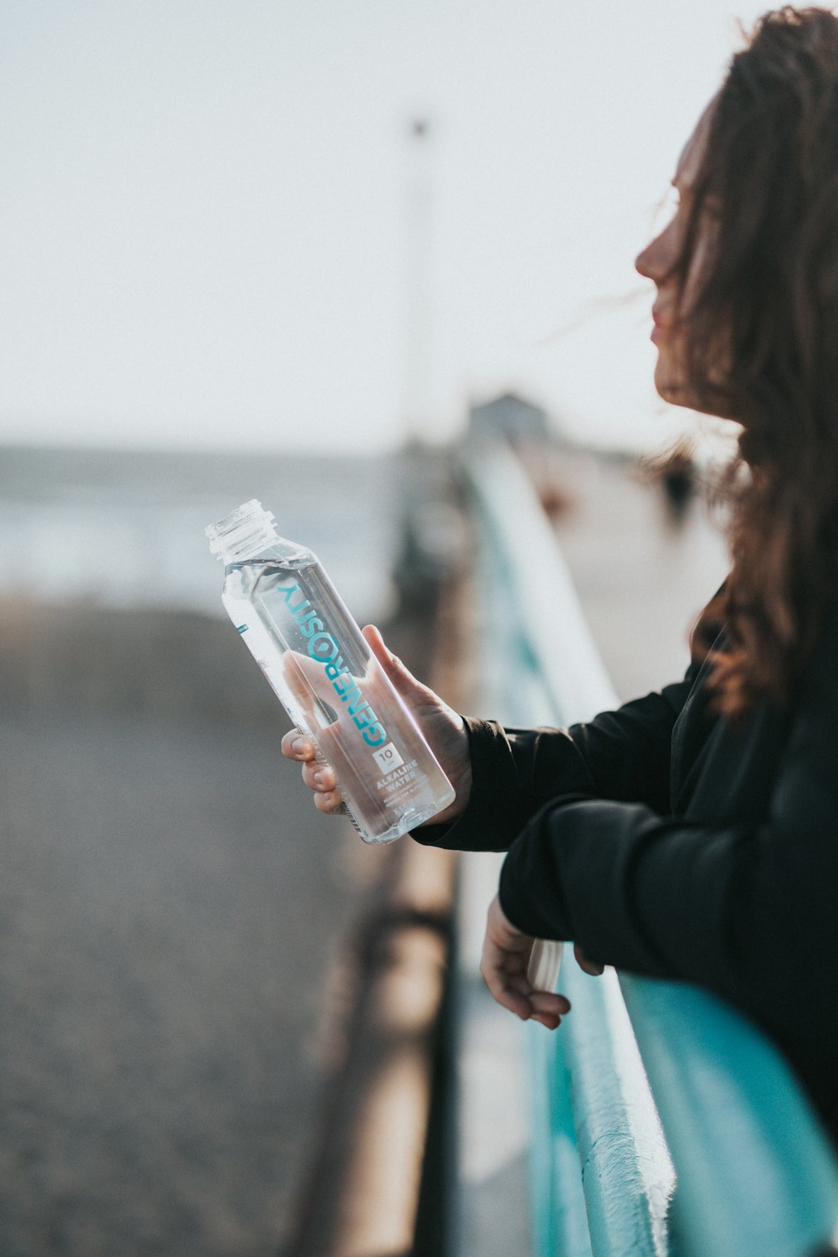 woman in black long sleeve shirt holding white plastic bottle