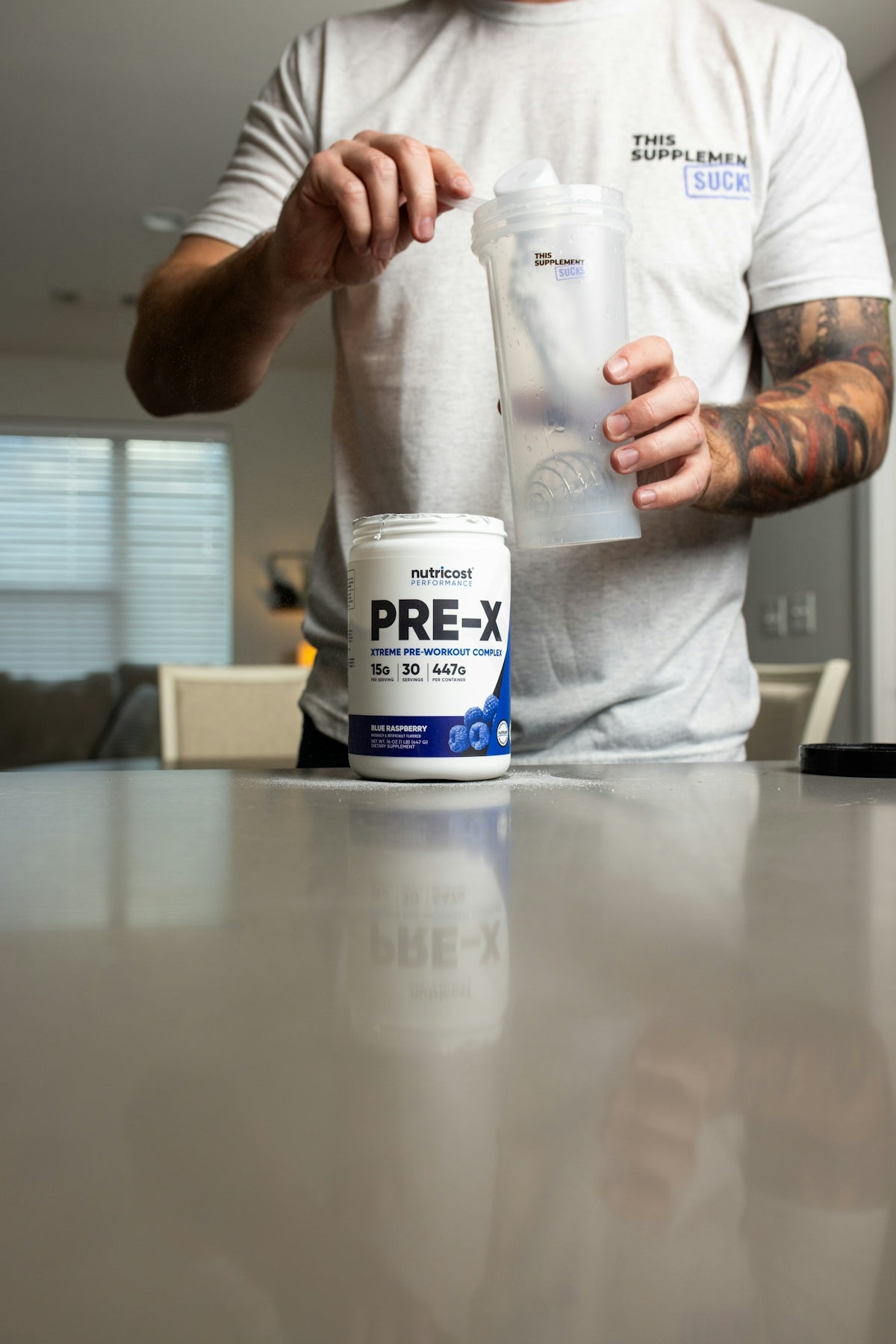 a man with a tattoo on his arm is holding a container of pre - x