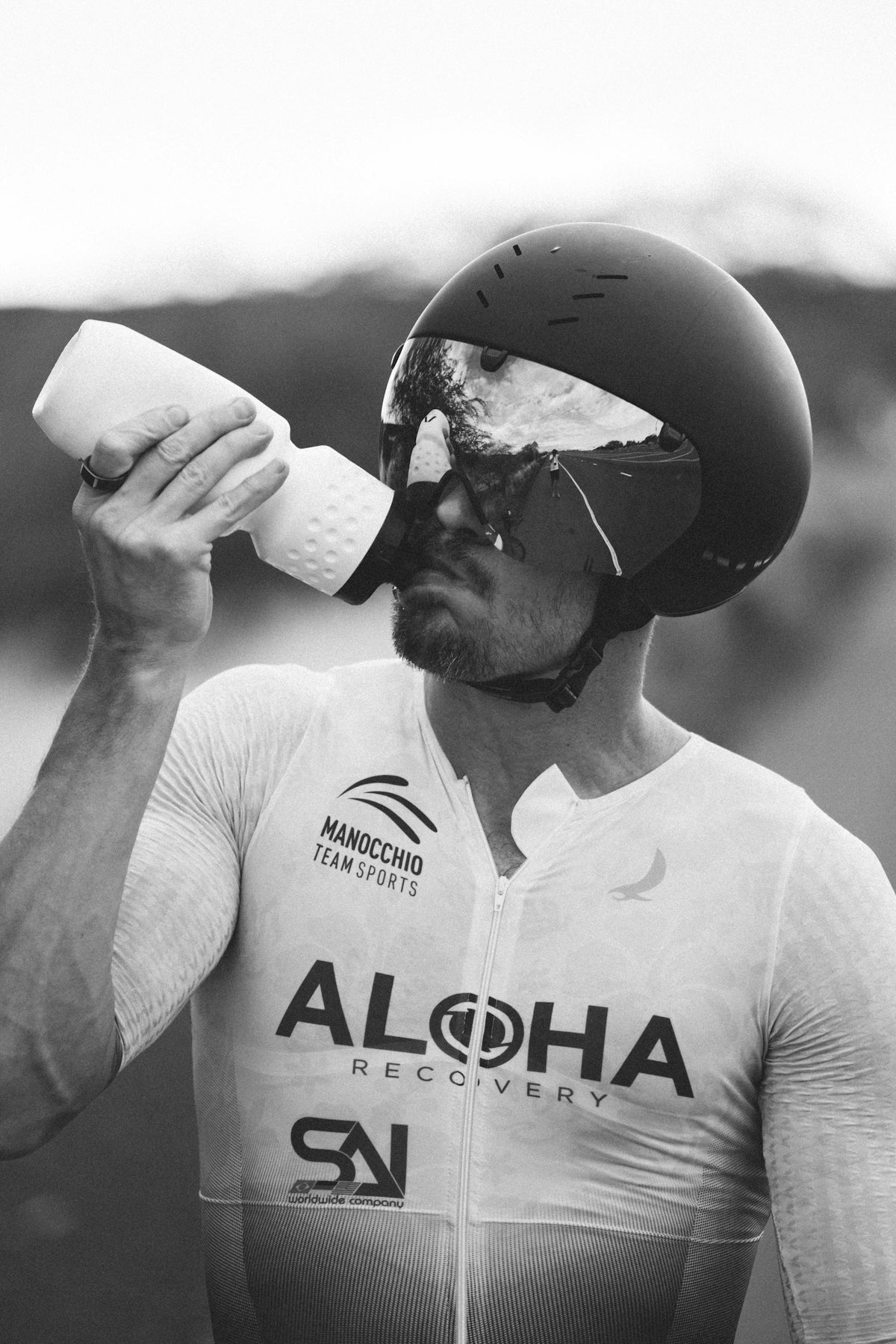 A man wearing a helmet drinking from a cup