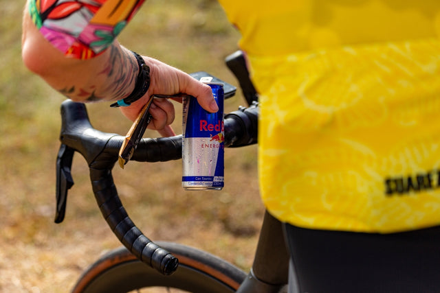 Cyclist drinks red bull during a break.