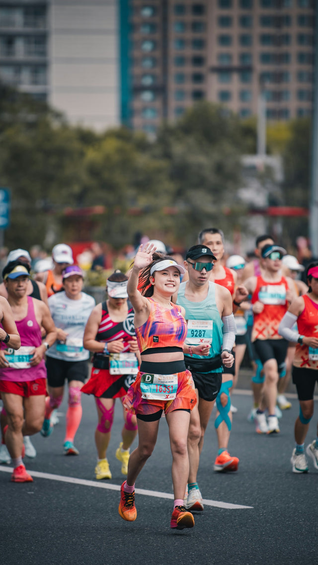 Woman waves while running in a marathon race.