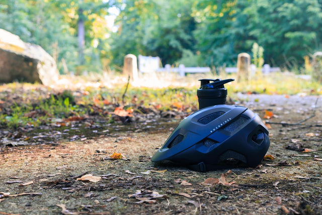 Dark blue bicycle helmet and water bottle on trail