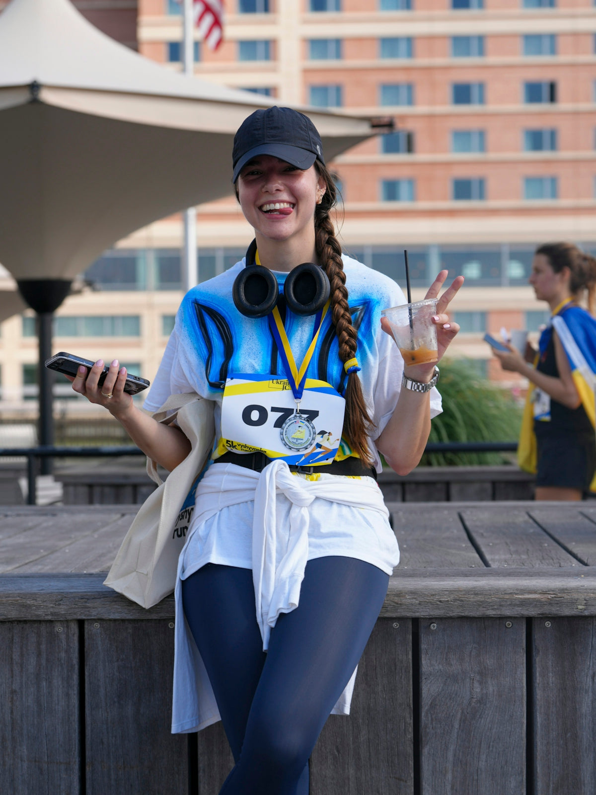 Smiling woman in running gear holding drink and phone