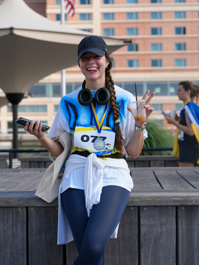 Smiling woman in running gear holding drink and phone