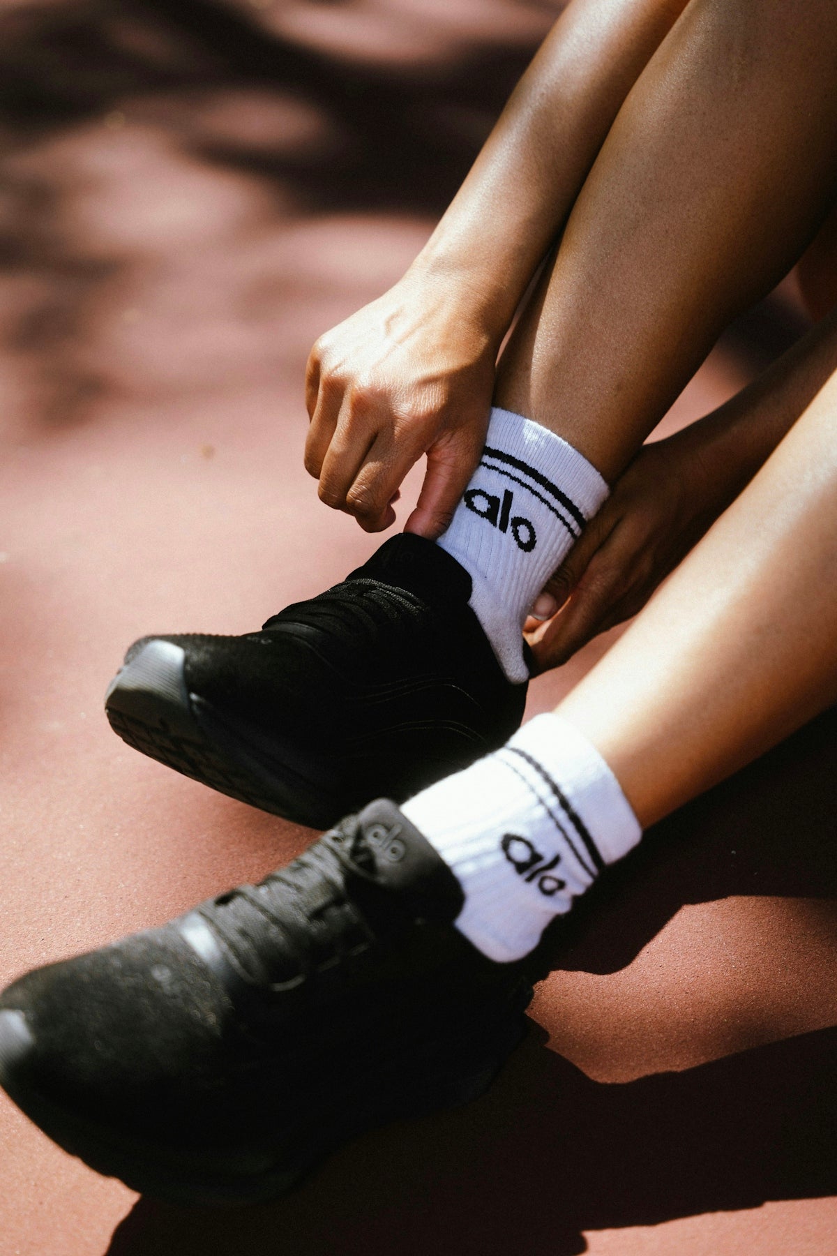 Person tying black athletic shoes with white socks