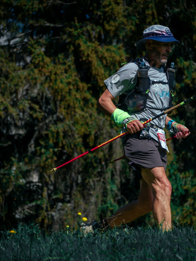 Man trail running with poles in a forest.
