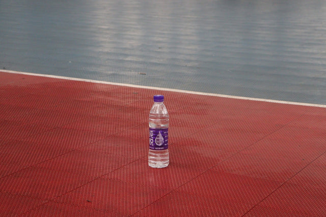Clear water bottle on a red sports court.