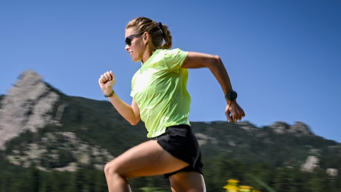 Woman running on a grassy field with mountains in the background
